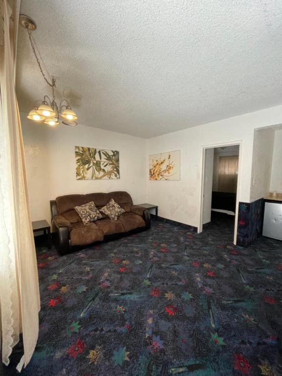 Living area with patterned carpet, brown sofa, and wall art.