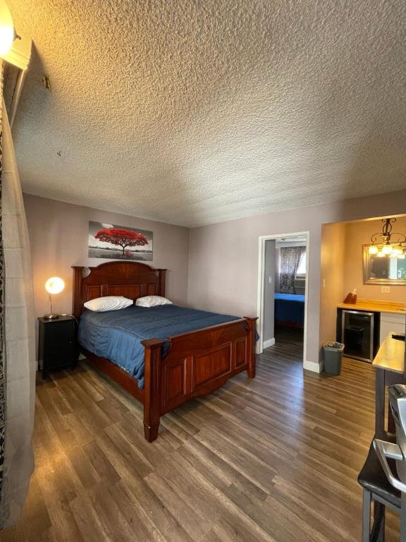 Room with wooden flooring, bed, and small kitchenette area.